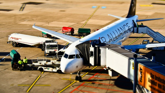 An airplane at the terminal with ground crew loading baggage