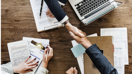two businessmen shaking hands across a table to indicate trust
