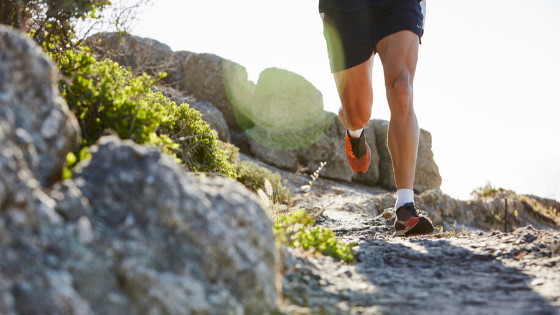trail runner with sneakers running on a rocky path