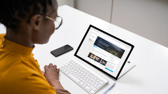 Professional womansitting at a desk attending a virtual event on her tablet