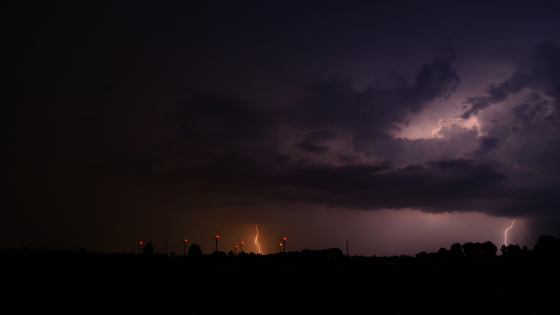 Evening thunderstorms and a wind farm with large wind turbines with red lights in the distance